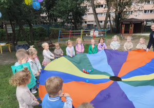 Dzieci bawią się kolorową chustą animacyjną.