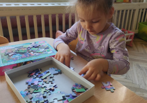 Dziewczynka układa puzzle.