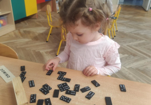 Dziewczynka układa domino.