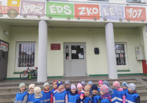 Grupowe zdjęcie na tle przedszkola.