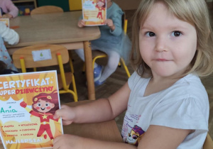 Dziewczynka trzyma dyplom.