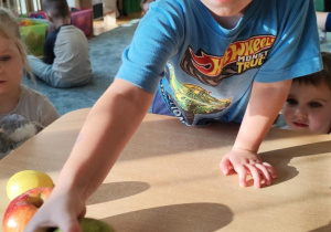 Chłopiec podaje gruszkę.