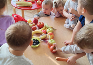 Dzieci układają na stole przyniesione przez siebie owoce i warzywa.