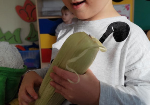 Chłopiec trzyma kukurydzę.