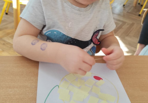 Dziewczynka wykleja gruszkę bibułą.