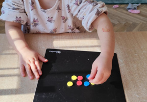 Dziewczynka układa kolorowe kółeczka.