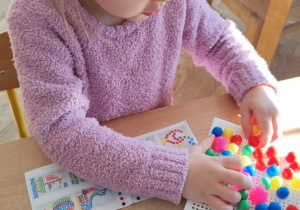 Dziewczynka układa kolorową mozaikę.