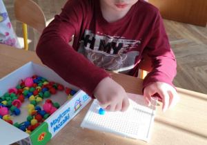 Chłopiec układa kolorową mozaikę.