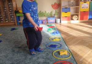 Chłopiec klasyfikuje woreczek w kolorze czerwonym.