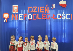 Dzieci pozują na granatowym tle z napisem Dzień Niepodległości.