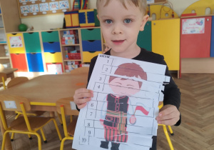 Chłopiec pokazuje wykonane puzzle ze strojem kaszubskim.