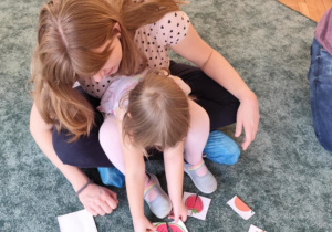 Dziewczynka z mamą układa owocowe puzzle.