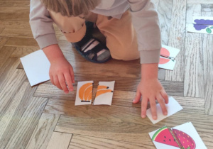 Chłopiec układa połówki owoców.