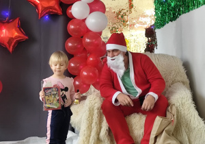 Dziewczynka pozuje do zdjęcia ze świętym Mikołajem.