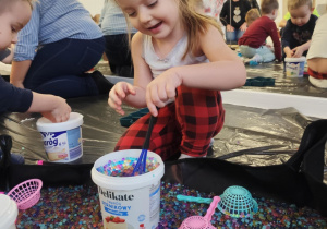 Dzieci bawią się żelowymi kuleczkami.