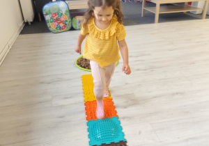 Dziewczynka przechodzi po torze sensorycznym.