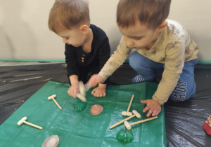 Dzieci wydobywają z lodu zamrożone figurki.