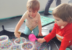 Dzieci bawią się żelowymi kuleczkami.