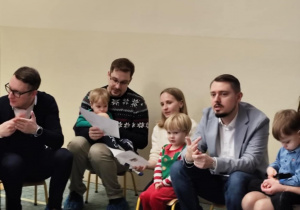 Dzieci z rodzicami śpiewają kolędy.
