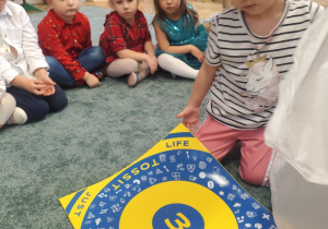 Dzieci oglądają planszę do rzutek.