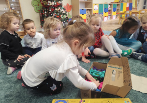 Dzieci rozpakowują prezent.