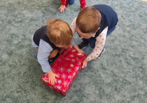 Dzieci rozpakowują prezent.