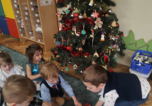 Dzieci odkrywają prezent ukryty pod choinką.