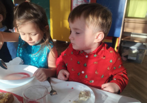 Dzieci próbują ryby, pierogów i kapusty z grochem.