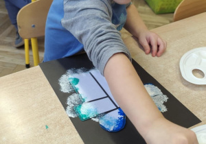 Chłopiec wykonuje pracę plastyczną.