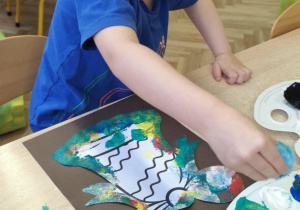 Chłopiec robi pracę plastyczną.