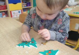 Chłopiec ozdabia choinkę.