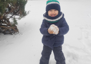 Chłopiec lepi śnieżkę.