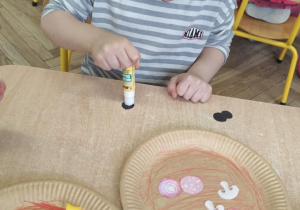 Chłopiec wykonuje własną pizzę.