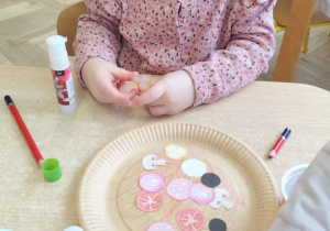 Dziewczynka wykonuje własną pizzę.