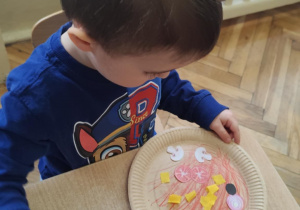 Chłopiec wykonuje własną pizzę.