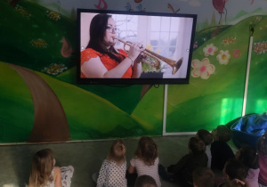 Dzieci oglądają film edukacyjny o trąbce.