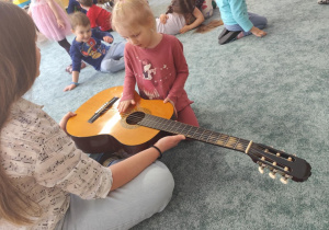Dziewczynka ogląda gitarę.