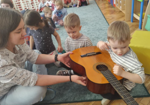 Chłopiec ogląda gitarę.