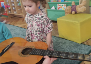 Dziewczynka ogląda gitarę.