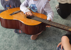 Dziewczynka ogląda gitarę.