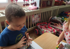 Dzieci naklejają kartoniki do ilustracji.