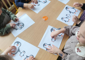 Dzieci układają sylwety pingwinów według poleceń nauczycielki.