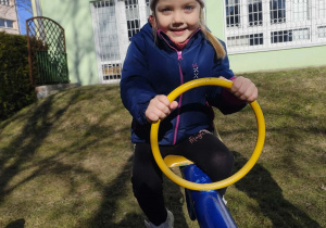 Dziewczynka buja się na koniku.