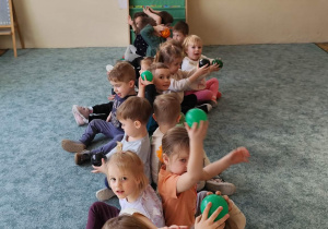 Dzieci podają sobie piłki nad głową