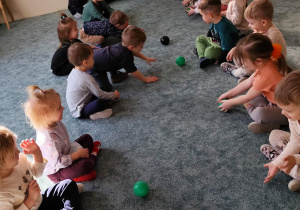 Dzieci turlają do siebie piłki