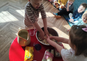 Dzieci ugniatają masę w misce.