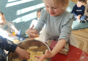 Dzieci ugniatają masę w misce.