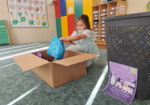 Dziewczynka wkłada dary do pudełka.