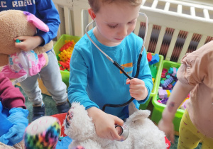 Chłopiec osłuchuje pluszowe zwierzątko stetoskopem.