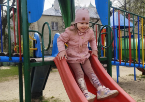 Dziewczynka zjeżdża ze zjeżdżalni.